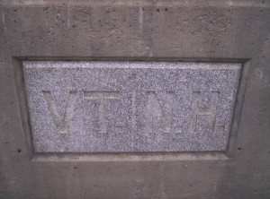The granite stone in the middle of the bridge across the river delineating the Vermont-New Hampshire state line, with VT | NH engraved in it